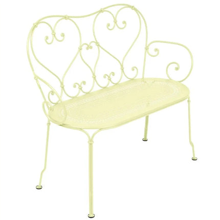 Colorful Fermob 1900 decorative bench with curved metal design and vibrant blue finish on a wooden patio.