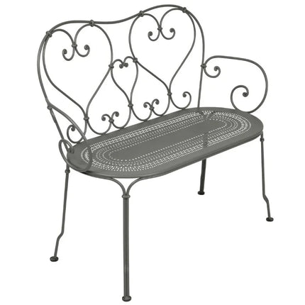 Colorful Fermob 1900 decorative bench with curved metal design and vibrant blue finish, ideal for indoor or outdoor seating.