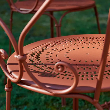 Fermob 1900 outdoor chair with a classic metal design, featuring curved armrests and a vibrant painted finish.