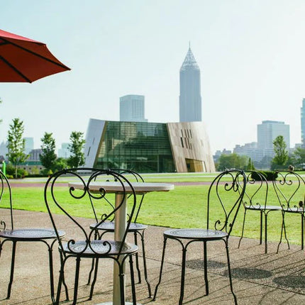 Fermob 1900 outdoor metal chair with curved backrest and armrests, designed for outdoor hospitality settings.