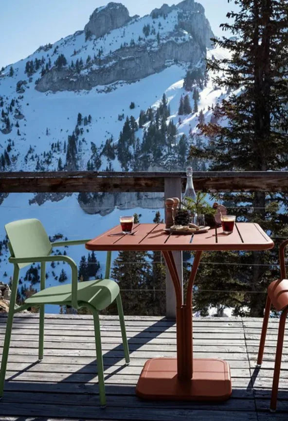 Dark red Fermob Luxembourg outdoor pedestal table, 80x80 cm with a sturdy metal frame and terracotta finish, ideal for outdoor spaces.