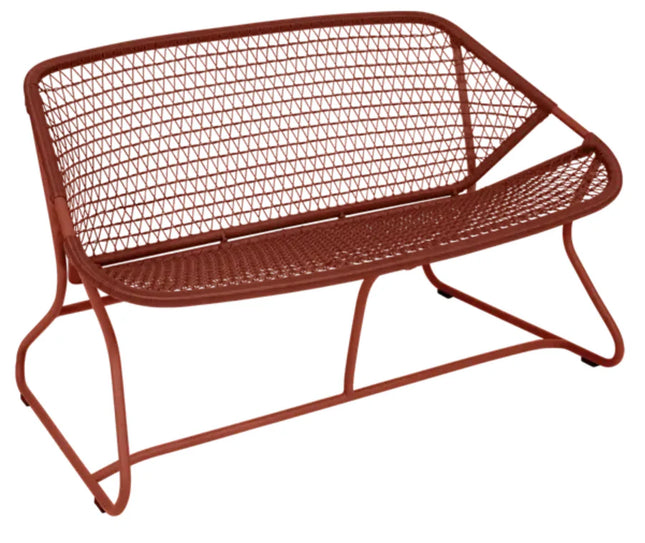 Red ochre Fermob Sixties outdoor sofa with a sleek, modern design, perfect for stylish outdoor furniture setups.